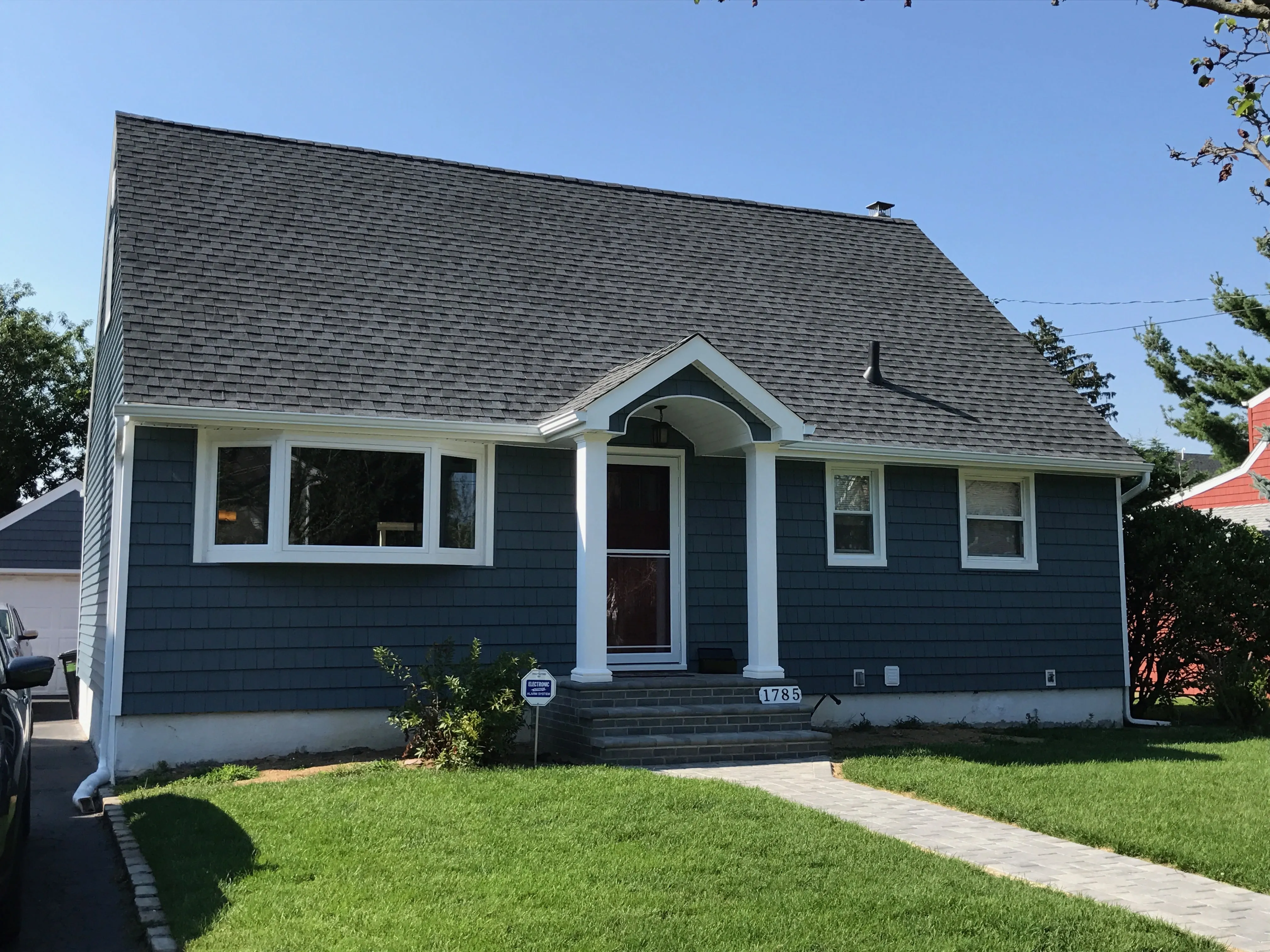Blue cape cod with horizontal vinyl siding, shake accents in the gable, stone veneer foundation, and dormer window